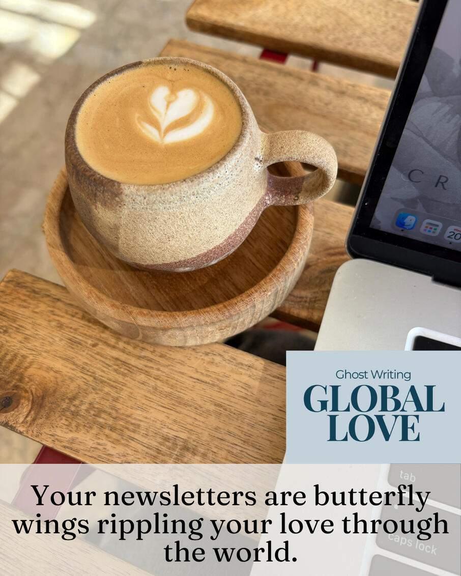 Coffee and Laptop in Tarifa Latte with heart foam art in a ceramic cup beside an open laptop on a wooden table, with the words "Your newsletter is butterfly wings rippling your love through the world."